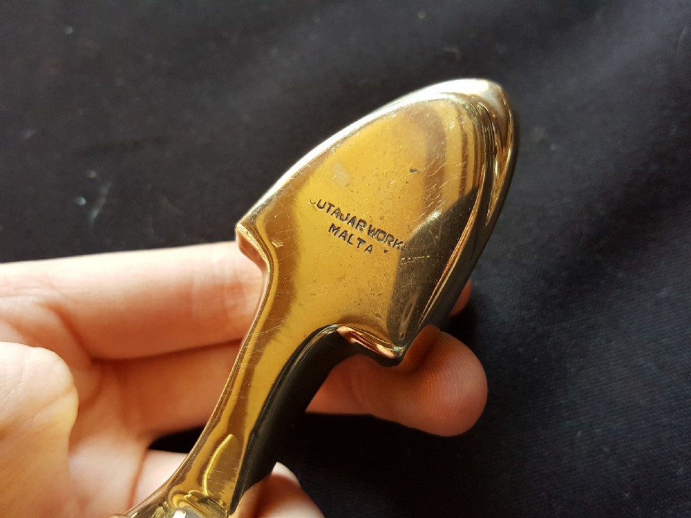 A polished brass door knocker shaped as a stylised dolphin mounted on a Maltese cross backplate alongside a separate brass striker button. View VII