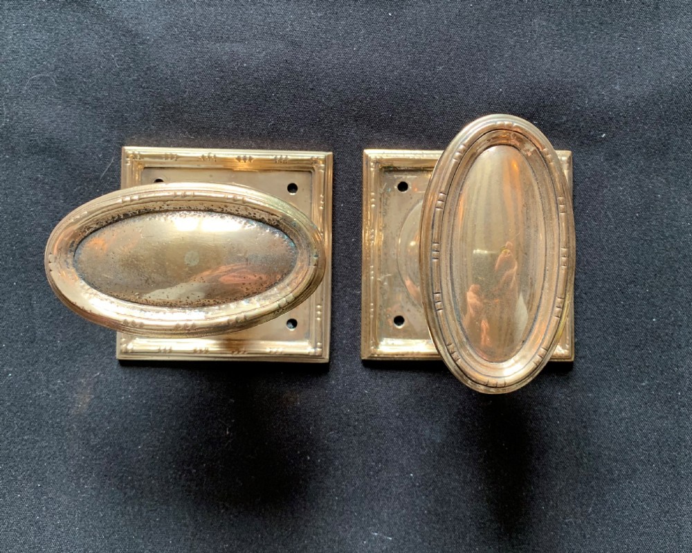 A pair of antique cast bronze oval door knobs mounted on square backplates with beaded borders. View II