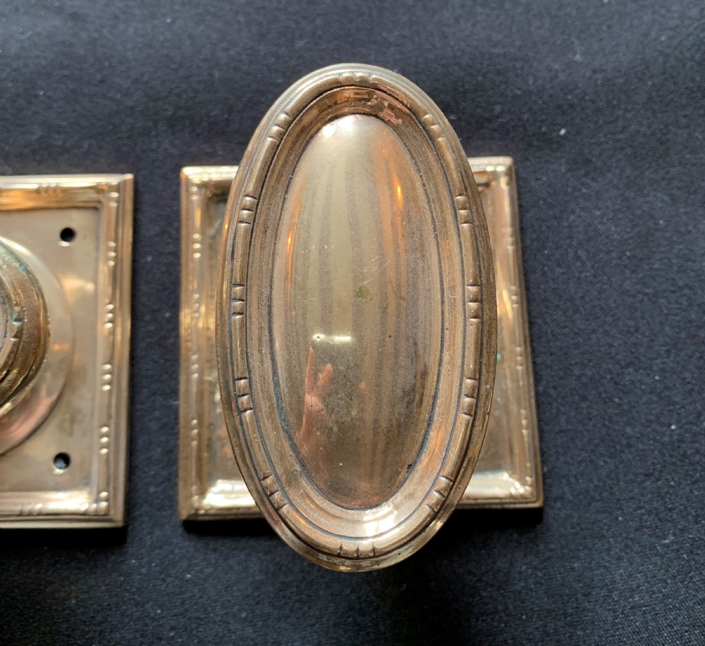 A pair of antique cast bronze oval door knobs mounted on square backplates with beaded borders. View III