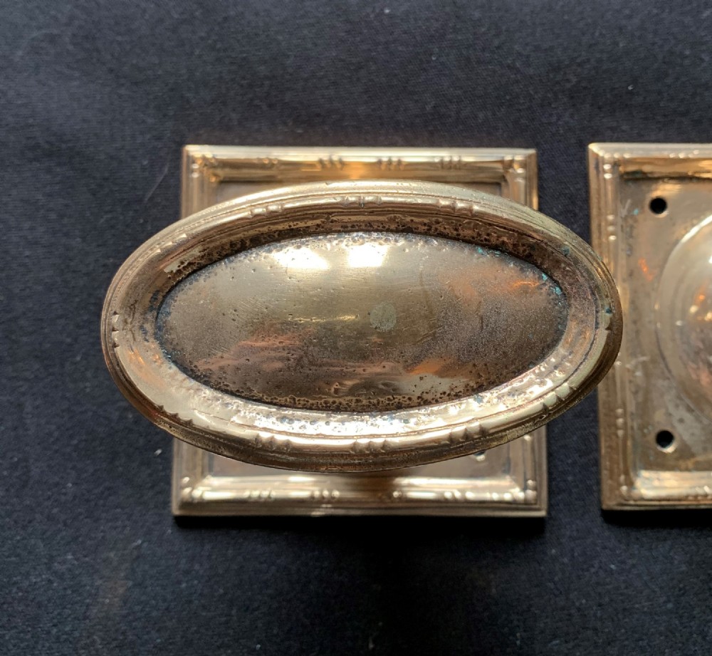 A pair of antique cast bronze oval door knobs mounted on square backplates with beaded borders. View IV