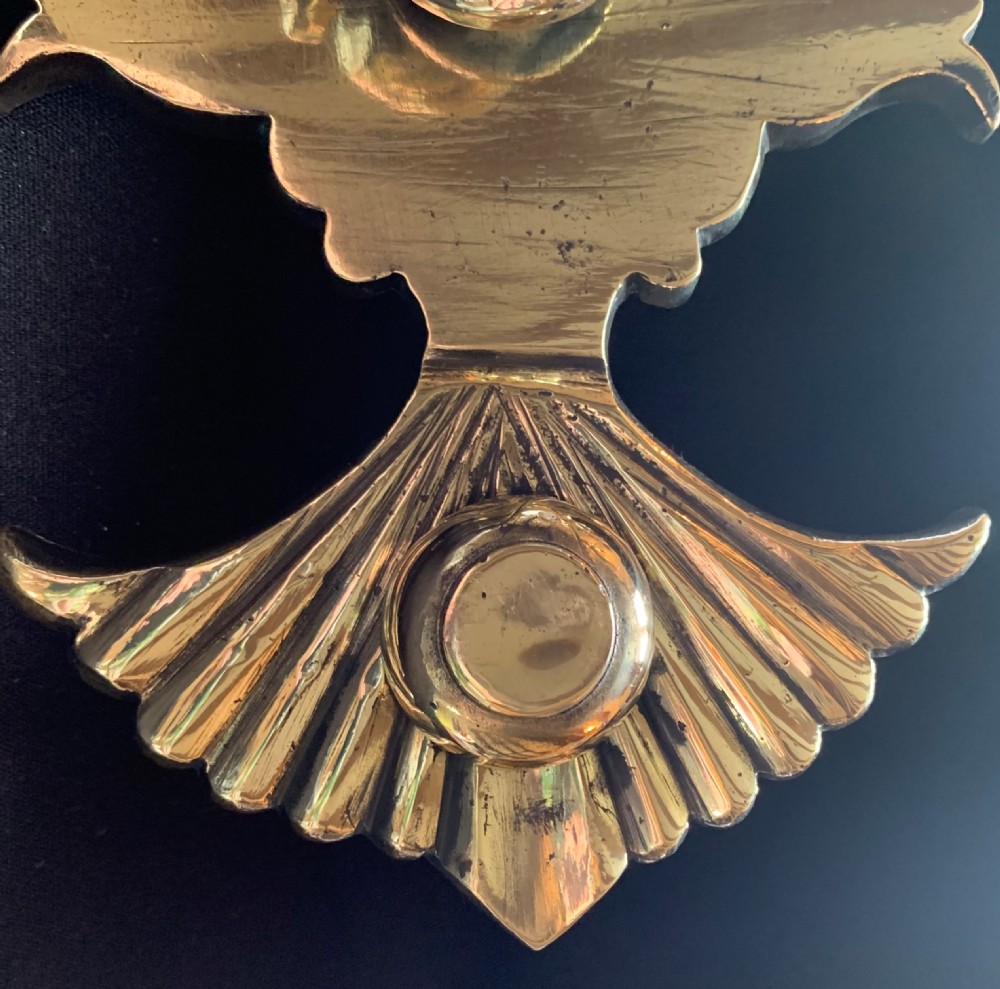 A polished solid brass Victorian door knocker featuring a heavy circular ring hinged above a fluted fan backplate. View III