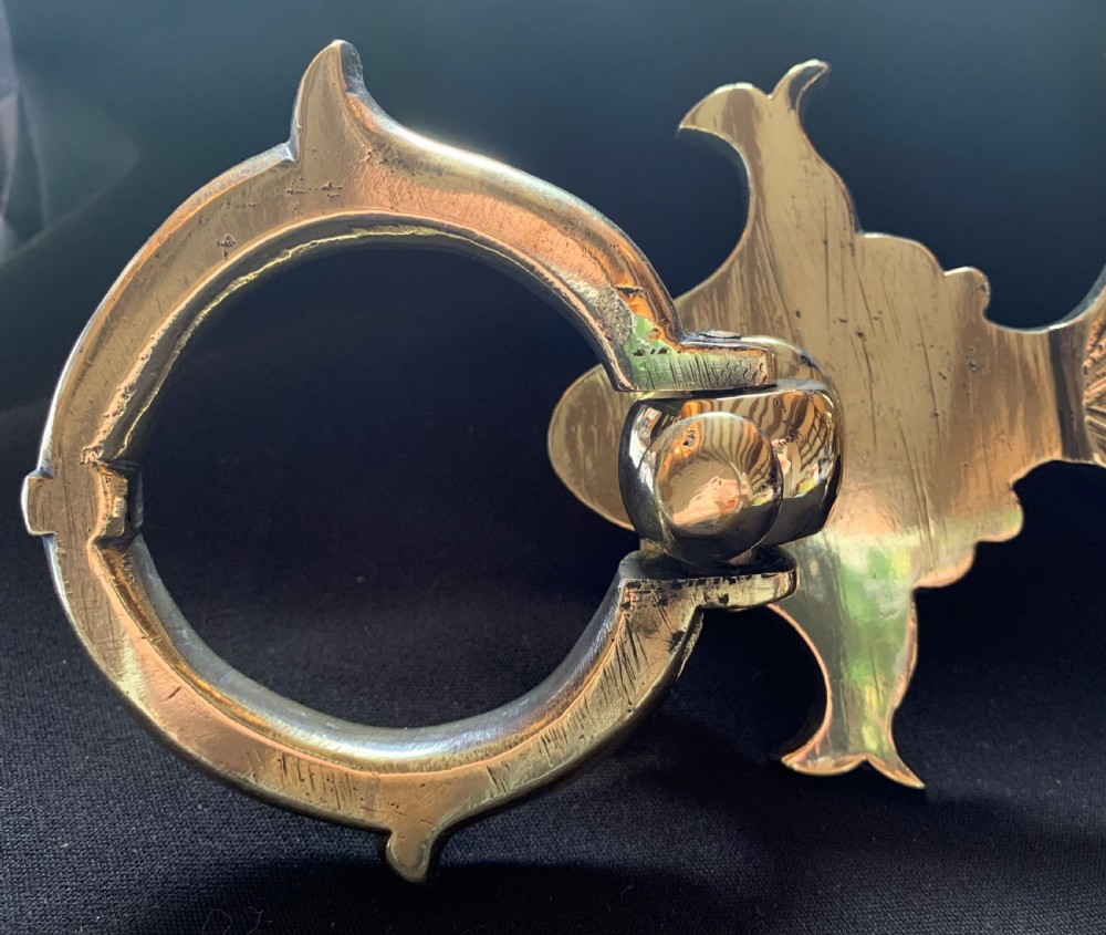 A polished solid brass Victorian door knocker featuring a heavy circular ring hinged above a fluted fan backplate. View IV
