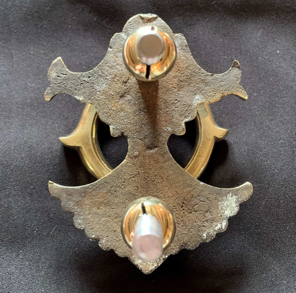 A polished solid brass Victorian door knocker featuring a heavy circular ring hinged above a fluted fan backplate. View V