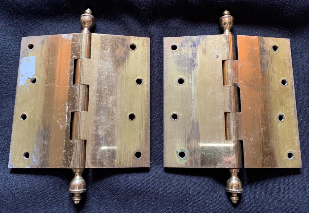 A pair of solid brass Victorian door hinges featuring decorative turned finials at both ends of each hinge pin. View V