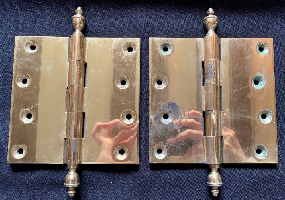 A pair of solid brass Victorian butt door hinges featuring turned urn finials at the top and bottom of each hinge pin. View V