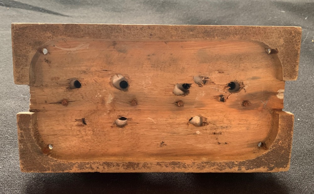 An antique Victorian double lever light switch featuring fluted brass domes on white porcelain bases, connected by a dark wooden lever bar on a timber backplate. View IV