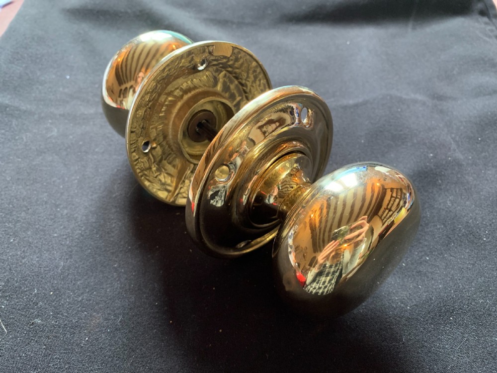 A pair of polished brass Georgian mortice door knobs complete with round rose plates and a connecting central steel spindle.