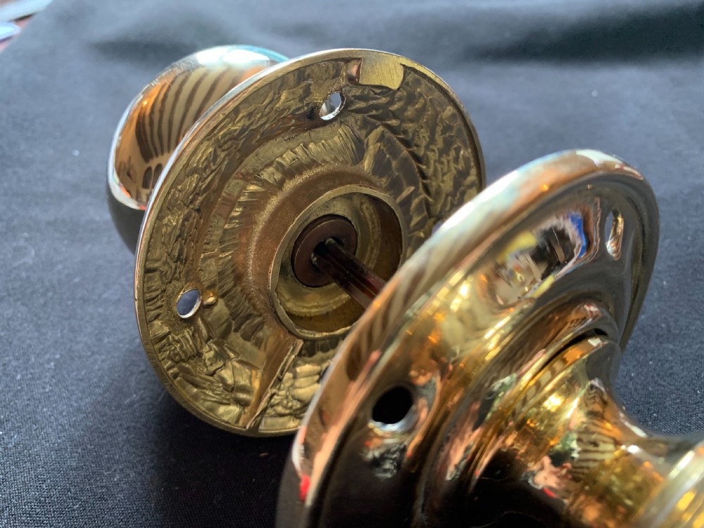 A pair of polished brass Georgian mortice door knobs complete with round rose plates and a connecting central steel spindle. View II