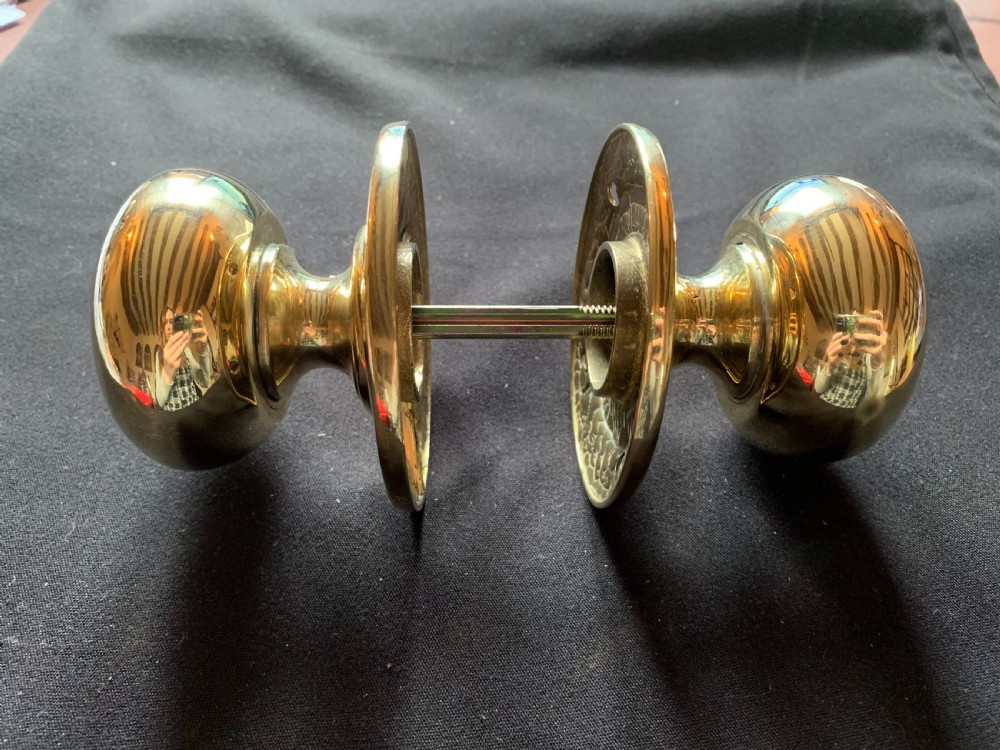 A pair of polished brass Georgian mortice door knobs complete with round rose plates and a connecting central steel spindle. View III