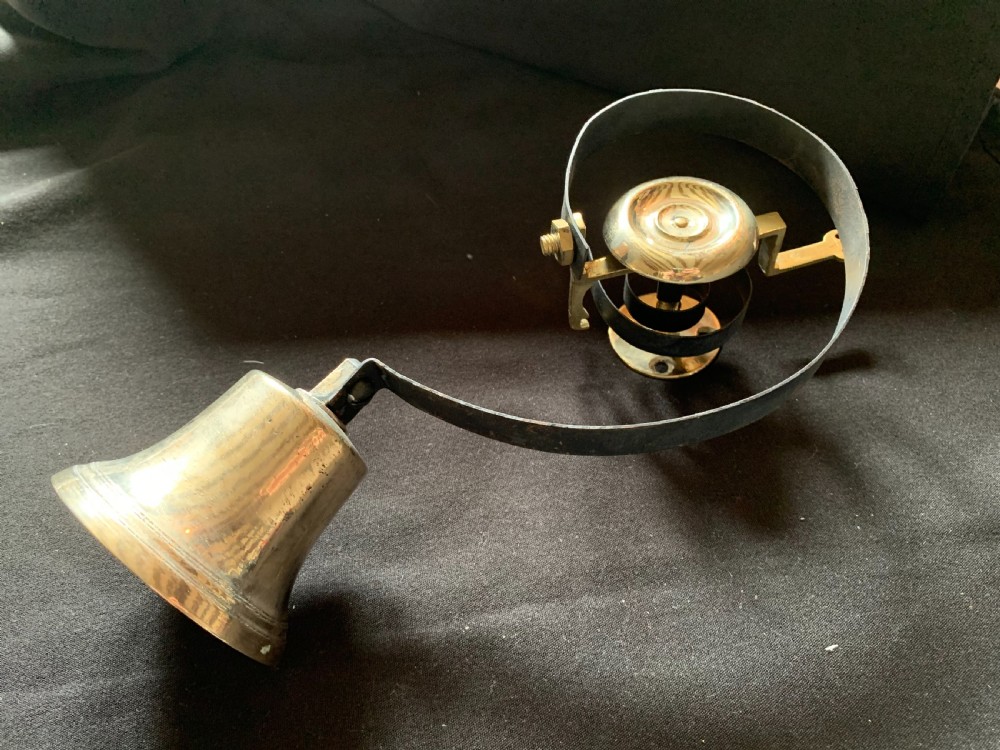 A restored Victorian mechanical servants bell featuring a polished brass bell suspended from a curved black steel spiral spring. View IV