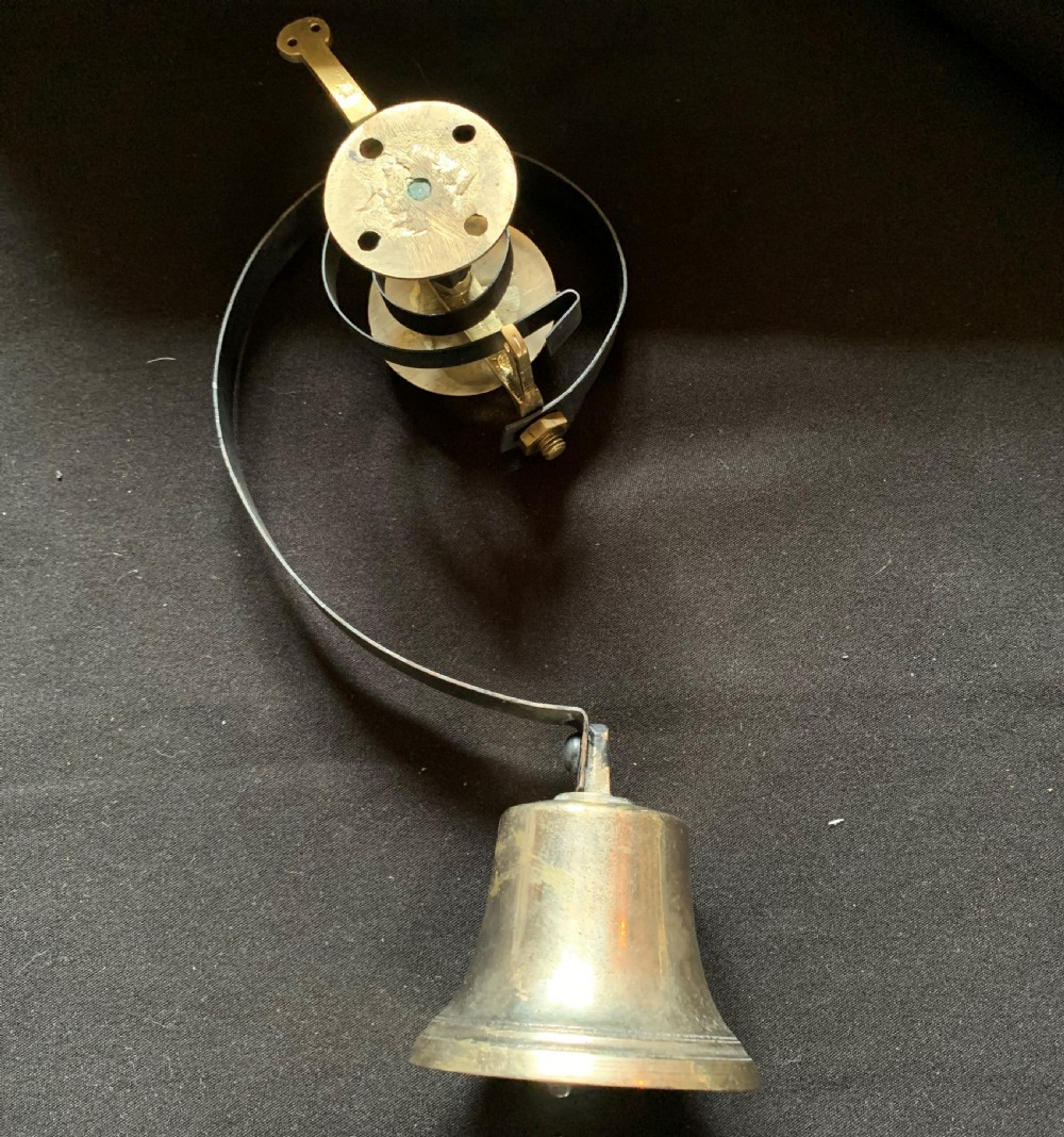 A restored Victorian mechanical servants bell featuring a polished brass bell suspended from a curved black steel spiral spring. View V