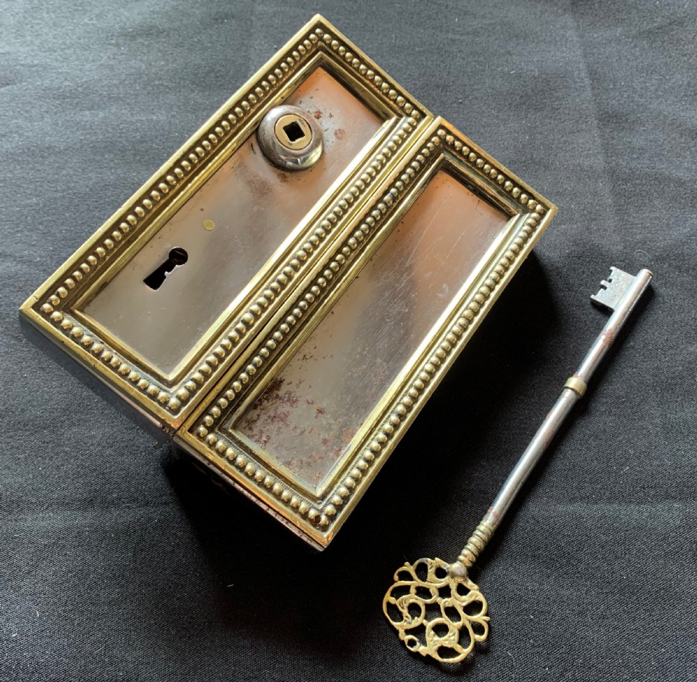 A rectangular French Victorian brass and polished steel rim lock with a beaded edge frame and an ornate matching key.