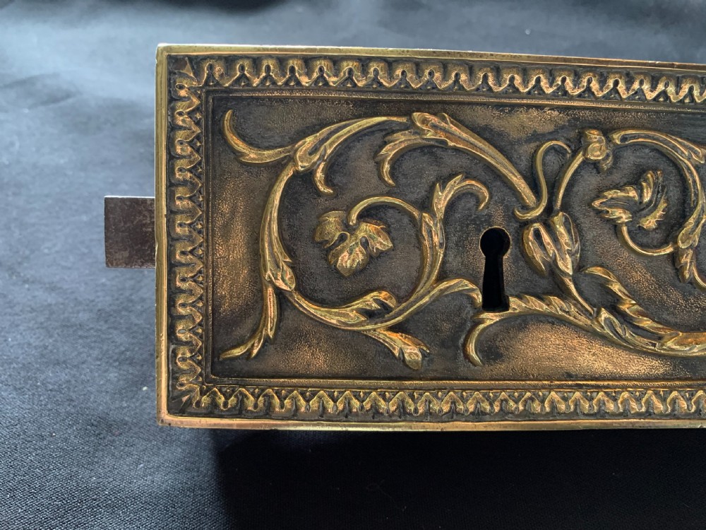 An ornate French Victorian brass rim lock set featuring raised foliate scrollwork, a matching keep, and two decorative keys. View IV
