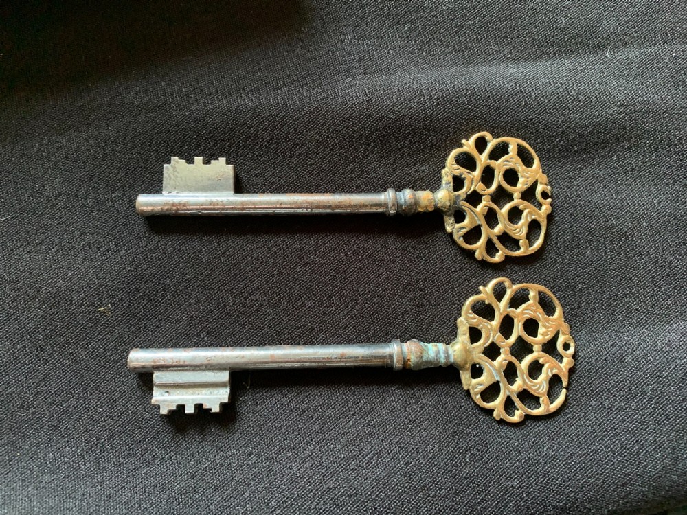 An ornate French Victorian brass rim lock set featuring raised foliate scrollwork, a matching keep, and two decorative keys. View VI