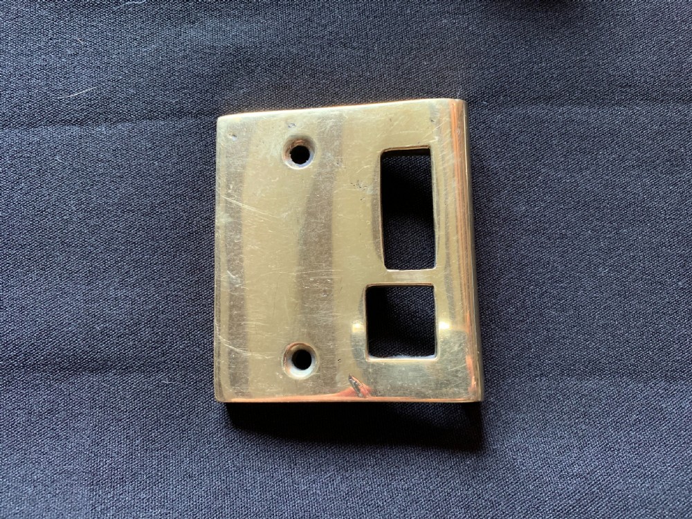 A polished brass Art Nouveau rim lock set featuring a rectangular surface lock, matching keep plate, and a pair of round fluted brass door knobs on a spindle. View IV