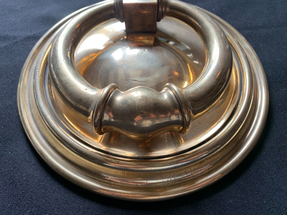 A circular polished brass Georgian door knocker with a heavy ring handle mounted on a moulded circular backplate. View III