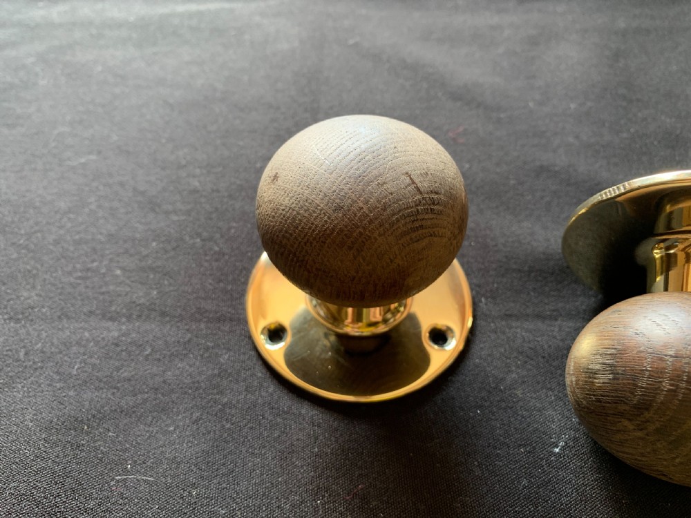 A pair of turned wooden door knobs featuring polished brass stems and circular backplates, shown with an iron connecting spindle. View II