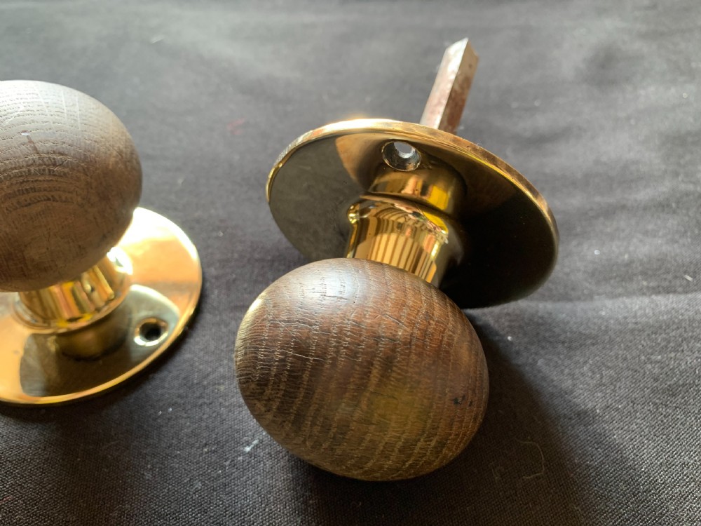 A pair of turned wooden door knobs featuring polished brass stems and circular backplates, shown with an iron connecting spindle. View IV