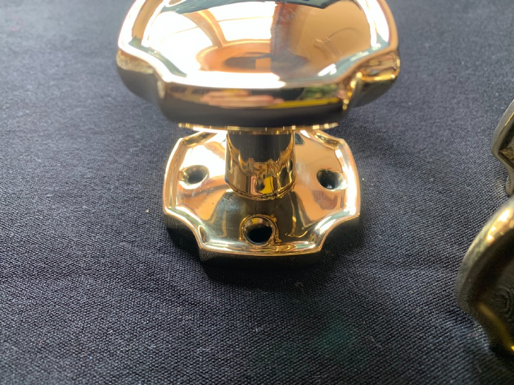 A pair of polished brass Victorian door knobs with square rose plates and a connecting spindle. View V