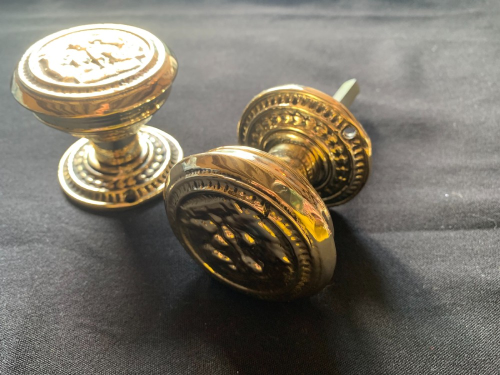 A pair of polished brass Victorian door knobs featuring raised embossed circular patterns and matching backplates. View II