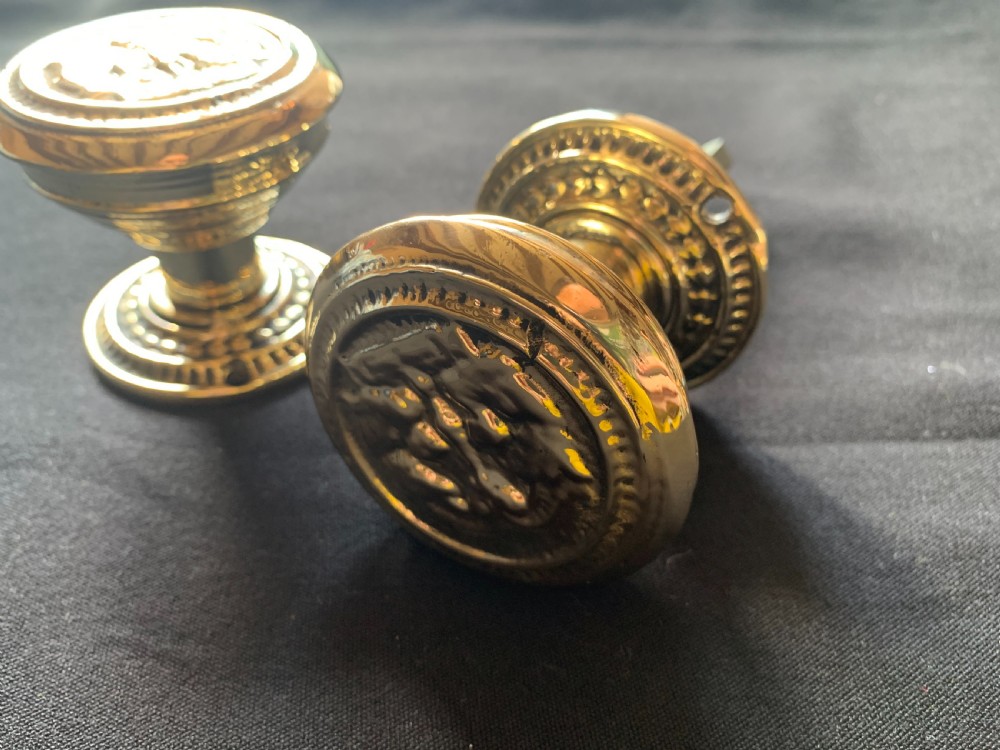 A pair of polished brass Victorian door knobs featuring raised embossed circular patterns and matching backplates. View III