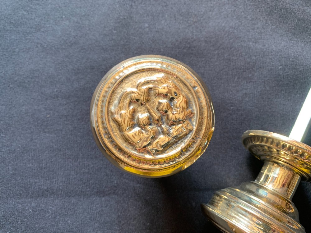 A pair of polished brass Victorian door knobs featuring raised embossed circular patterns and matching backplates. View IV
