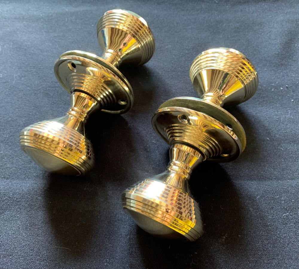 Two pairs of polished brass Victorian beehive door knobs with reeded bodies and circular rose plates.