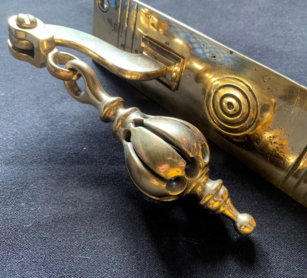 A brass Georgian mechanical doorbell pull featuring a rectangular backplate engraved with concentric circles and a bulbous drop handle. View IV