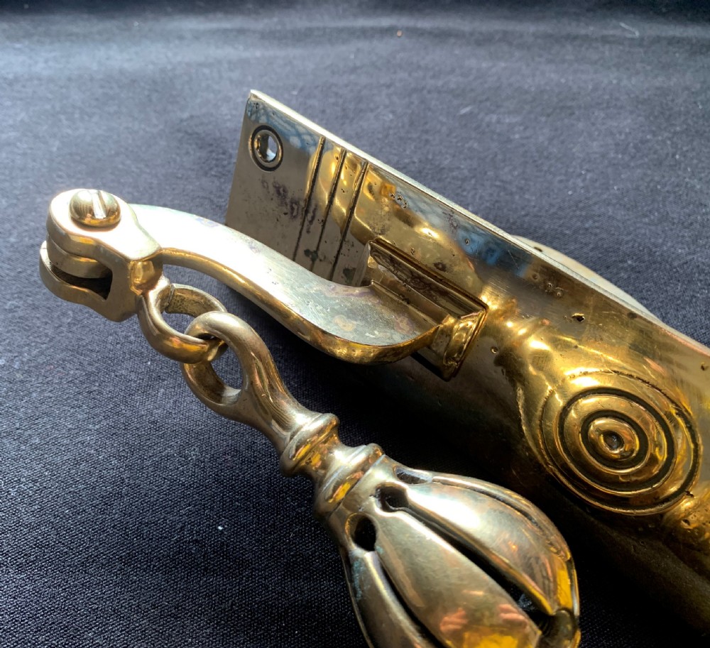 A brass Georgian mechanical doorbell pull featuring a rectangular backplate engraved with concentric circles and a bulbous drop handle. View V