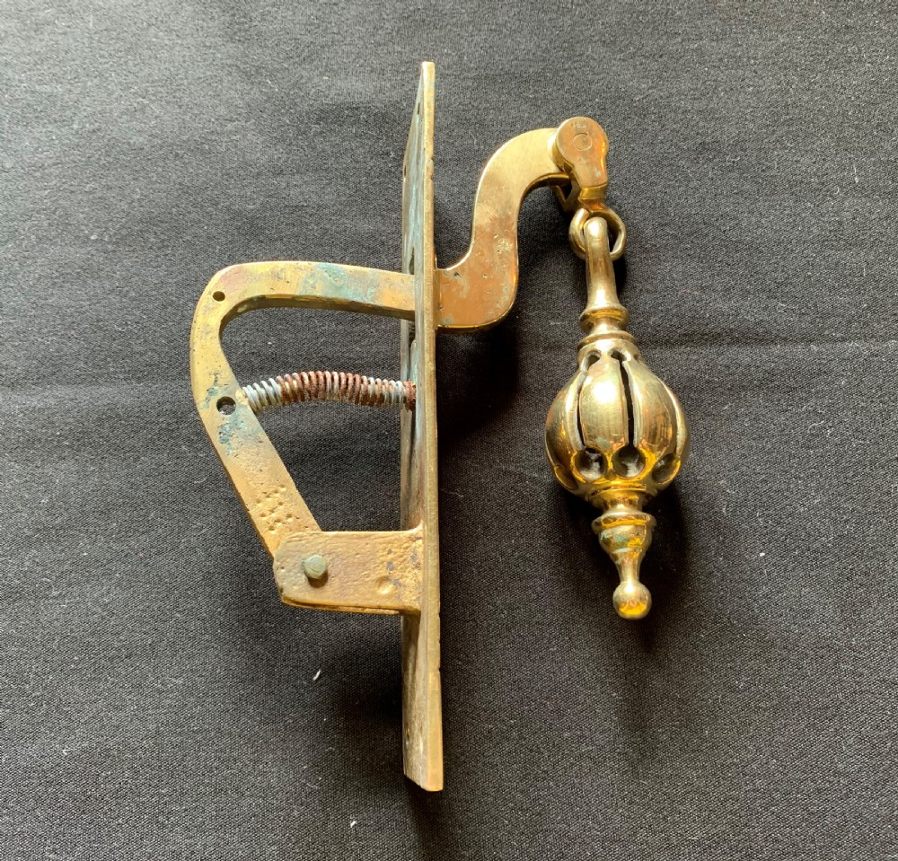 A brass Georgian mechanical doorbell pull featuring a rectangular backplate engraved with concentric circles and a bulbous drop handle. View VII