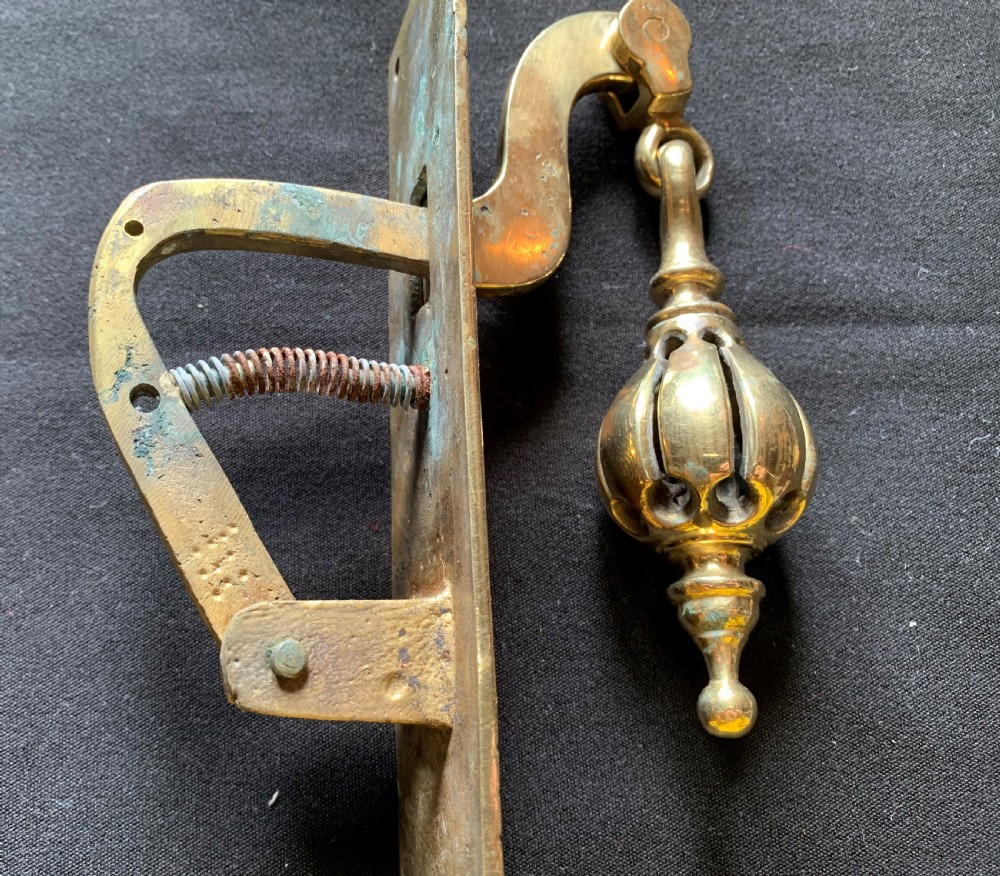 A brass Georgian mechanical doorbell pull featuring a rectangular backplate engraved with concentric circles and a bulbous drop handle. View IX