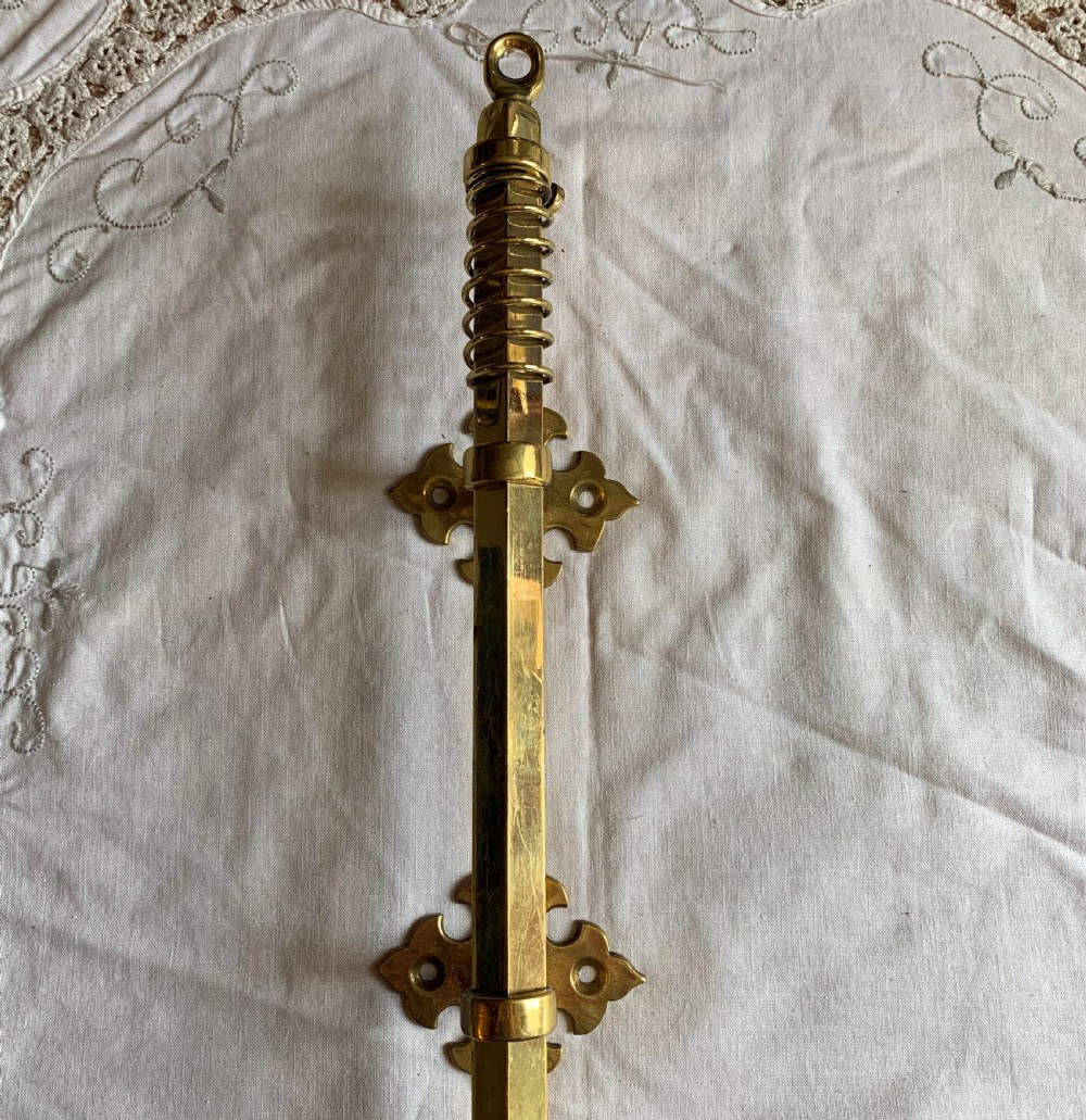 A restored Victorian mechanical door bell pull in polished brass featuring a spiral cage handle and twin decorative mounting brackets. View II