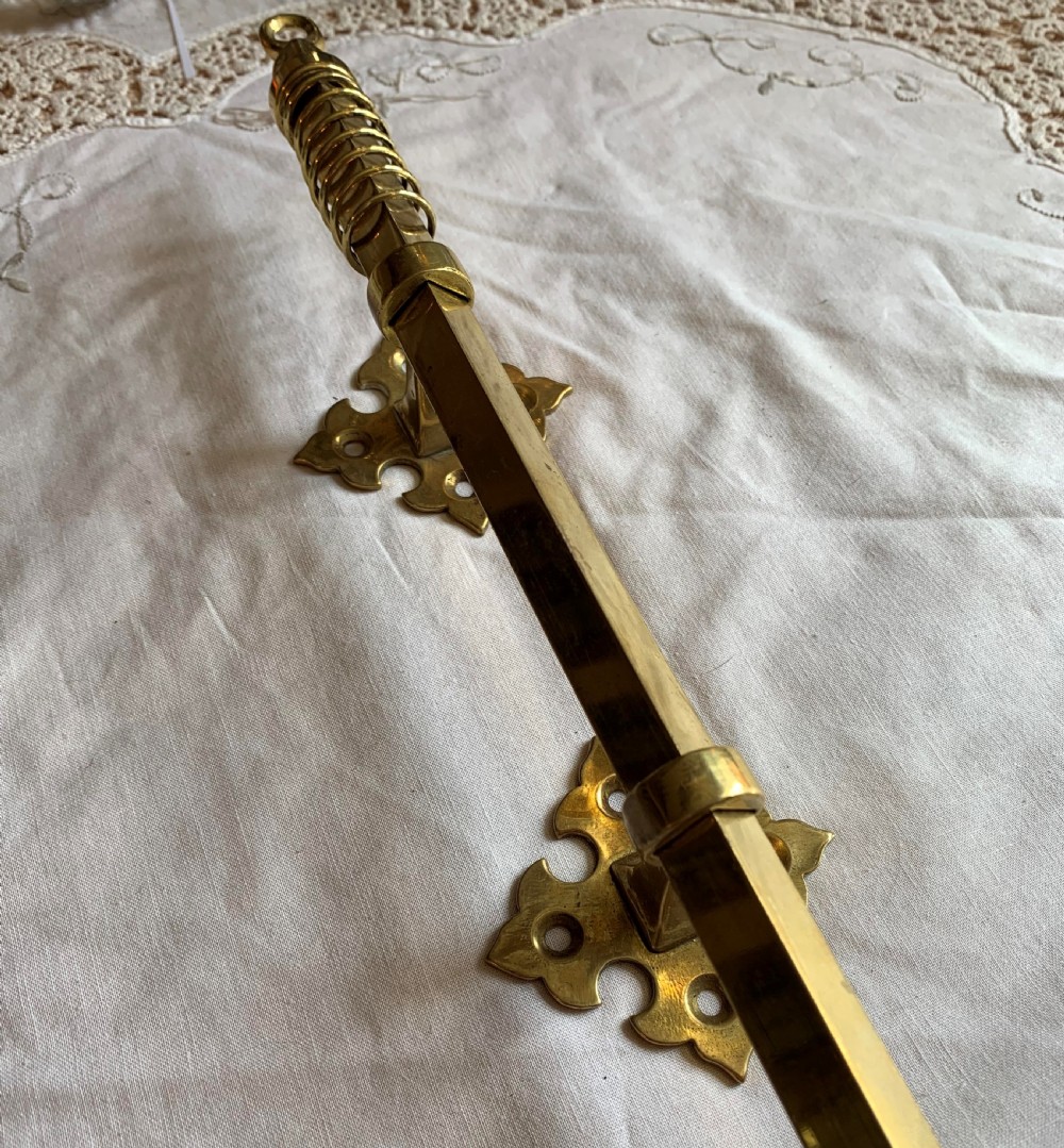 A restored Victorian mechanical door bell pull in polished brass featuring a spiral cage handle and twin decorative mounting brackets. View IV
