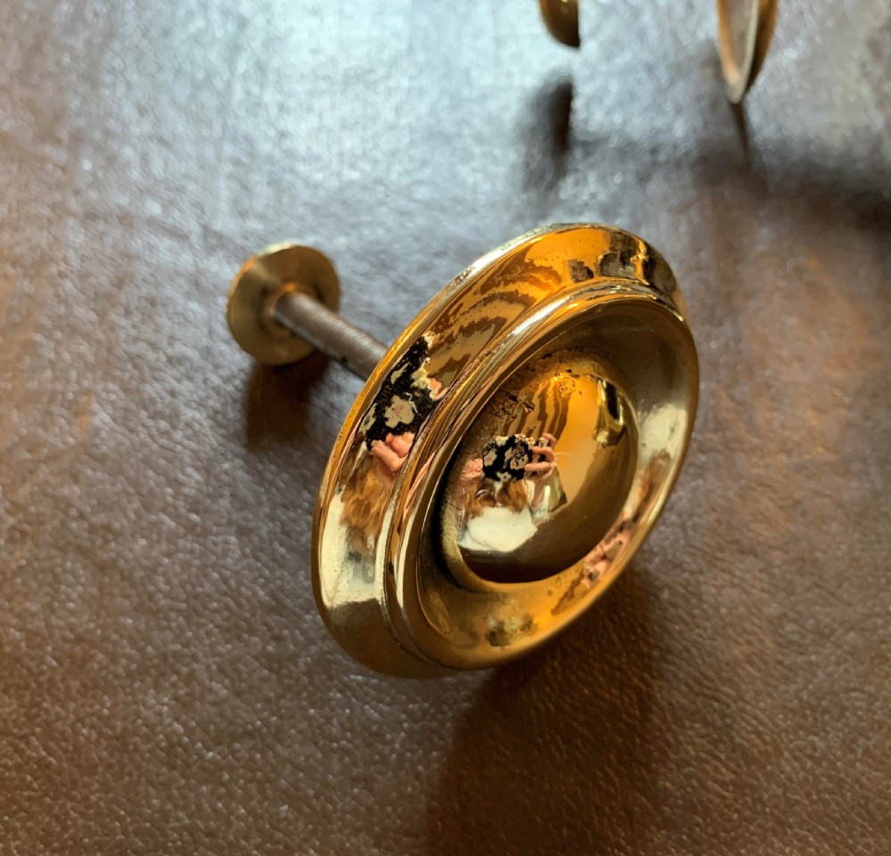 A solid polished brass door knocker styled as a Maltese dolphin, complete with a separate circular striker plate and threaded mounting bolts. View II