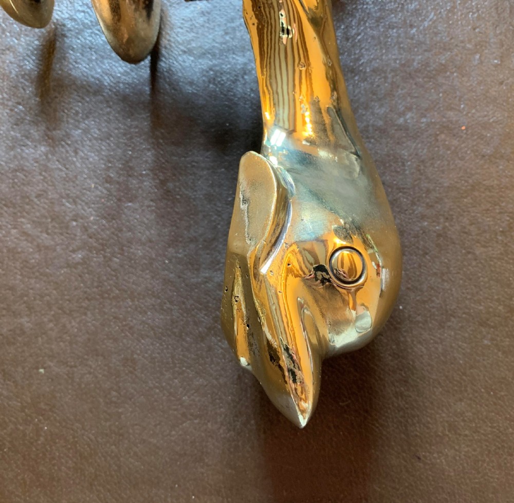 A solid polished brass door knocker styled as a Maltese dolphin, complete with a separate circular striker plate and threaded mounting bolts. View III