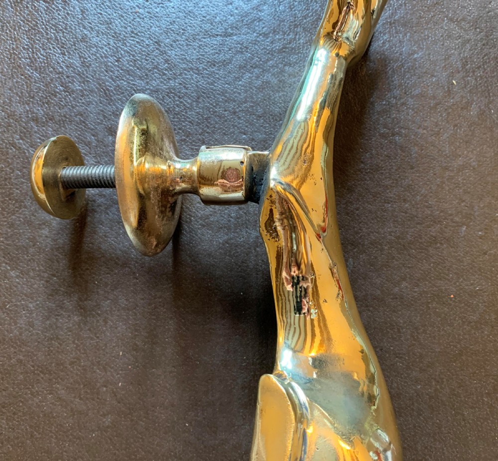 A solid polished brass door knocker styled as a Maltese dolphin, complete with a separate circular striker plate and threaded mounting bolts. View IV