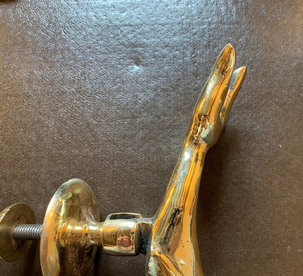 A solid polished brass door knocker styled as a Maltese dolphin, complete with a separate circular striker plate and threaded mounting bolts. View V