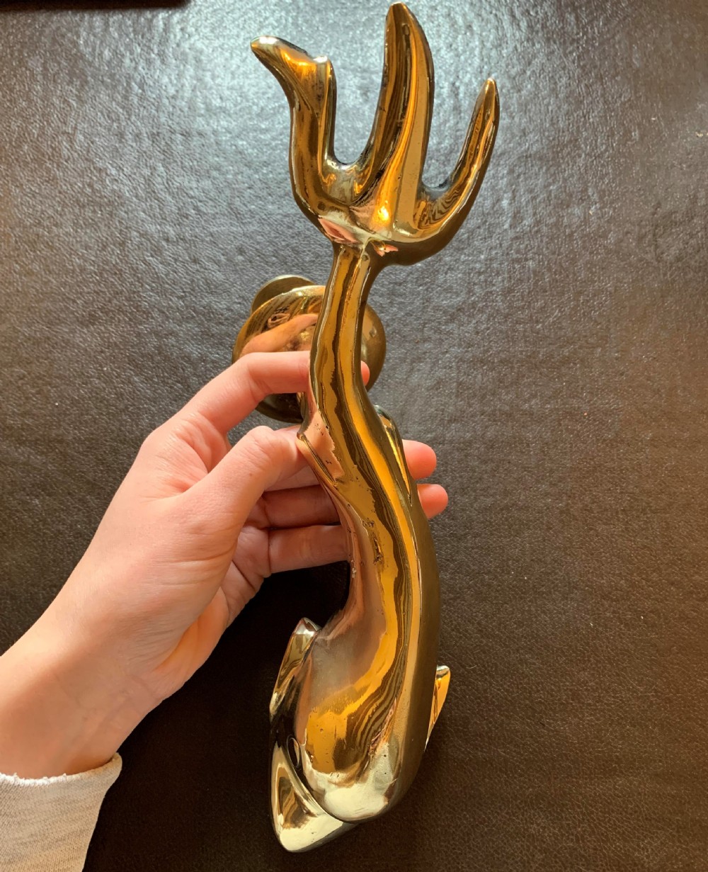 A solid polished brass door knocker styled as a Maltese dolphin, complete with a separate circular striker plate and threaded mounting bolts. View VI