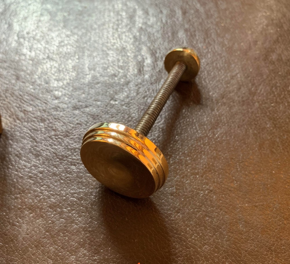 A cast polished brass door knocker sculpted in the shape of a Maltese dolphin alongside its circular striking plate and mounting bolts. View IV