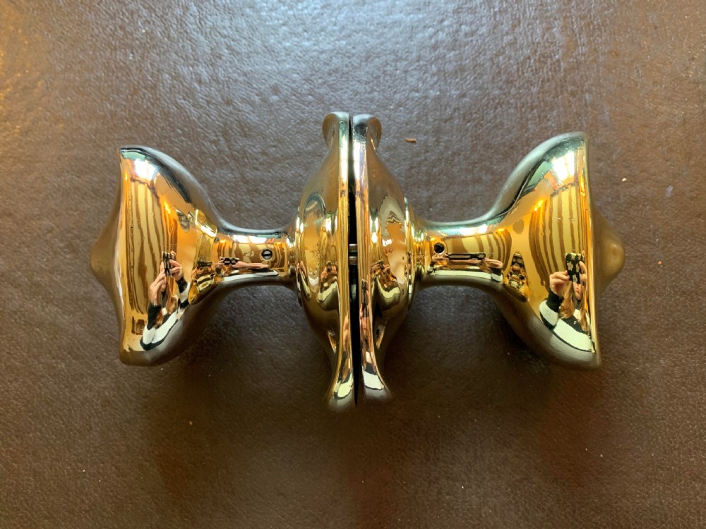 A pair of polished brass oval door knobs mounted on a spindle assembly with oval backplates. View II