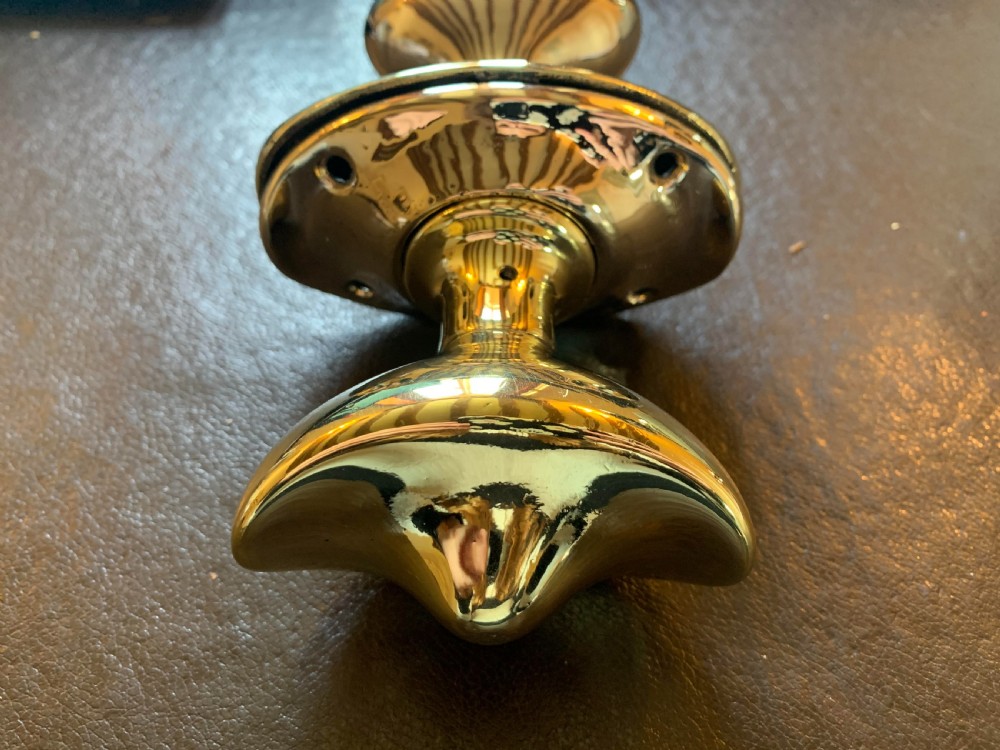 A pair of polished brass oval door knobs mounted on a spindle assembly with oval backplates. View III