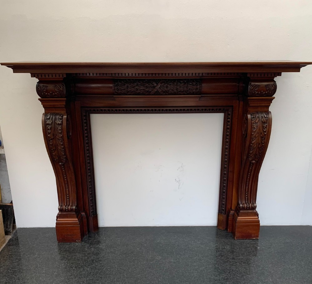 A Victorian carved mahogany fireplace surround featuring prominent acanthus leaf corbels, bead moulding, and a carved central frieze.