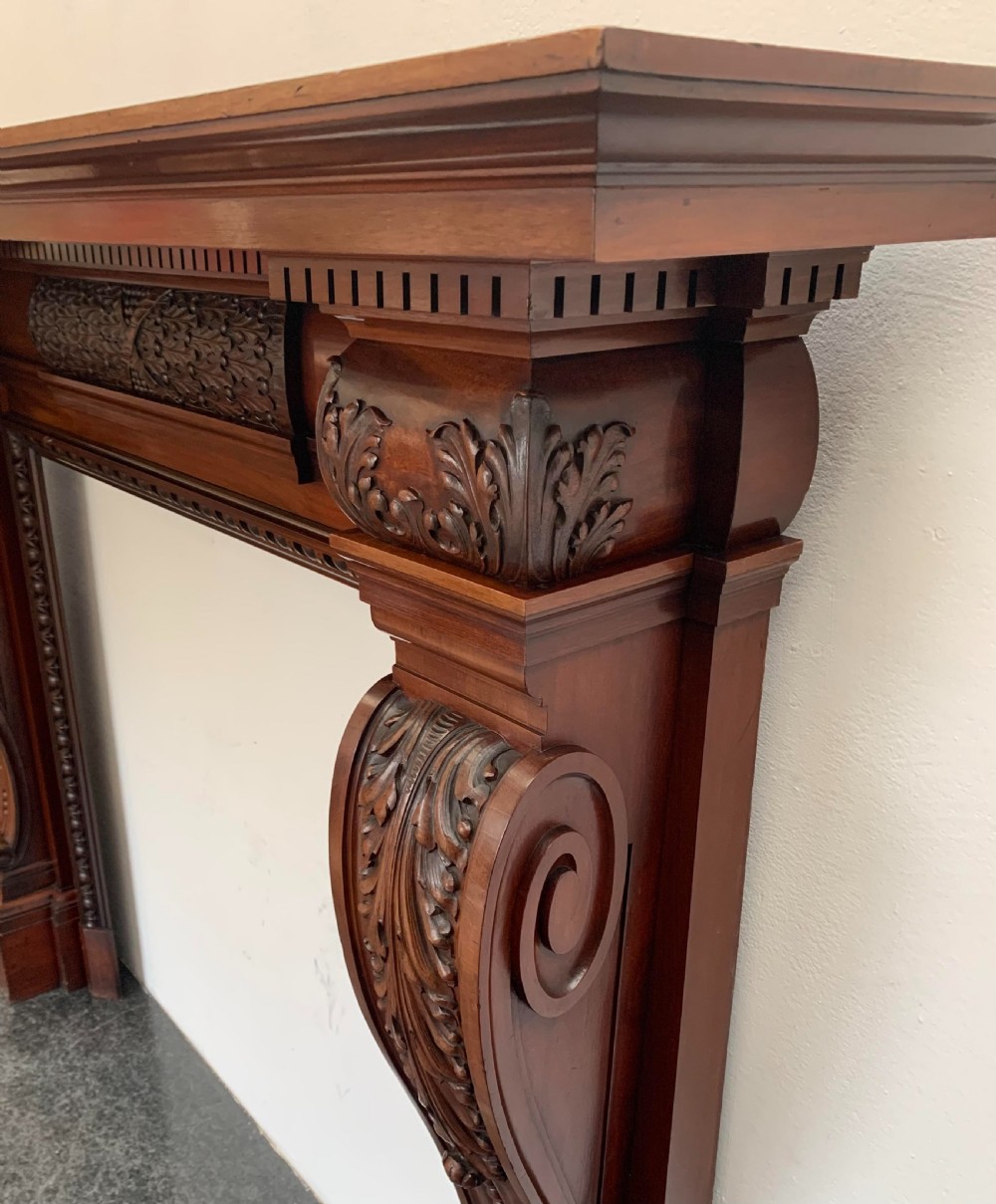 A Victorian carved mahogany fireplace surround featuring prominent acanthus leaf corbels, bead moulding, and a carved central frieze. View VI