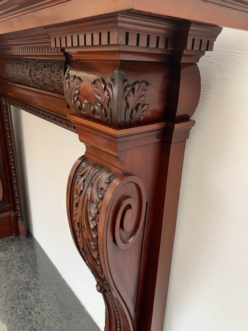 A Victorian carved mahogany fireplace surround featuring prominent acanthus leaf corbels, bead moulding, and a carved central frieze. View VII