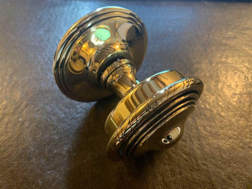 A polished brass centre door knob featuring a stepped circular backplate and a rope-twist detailed edge.