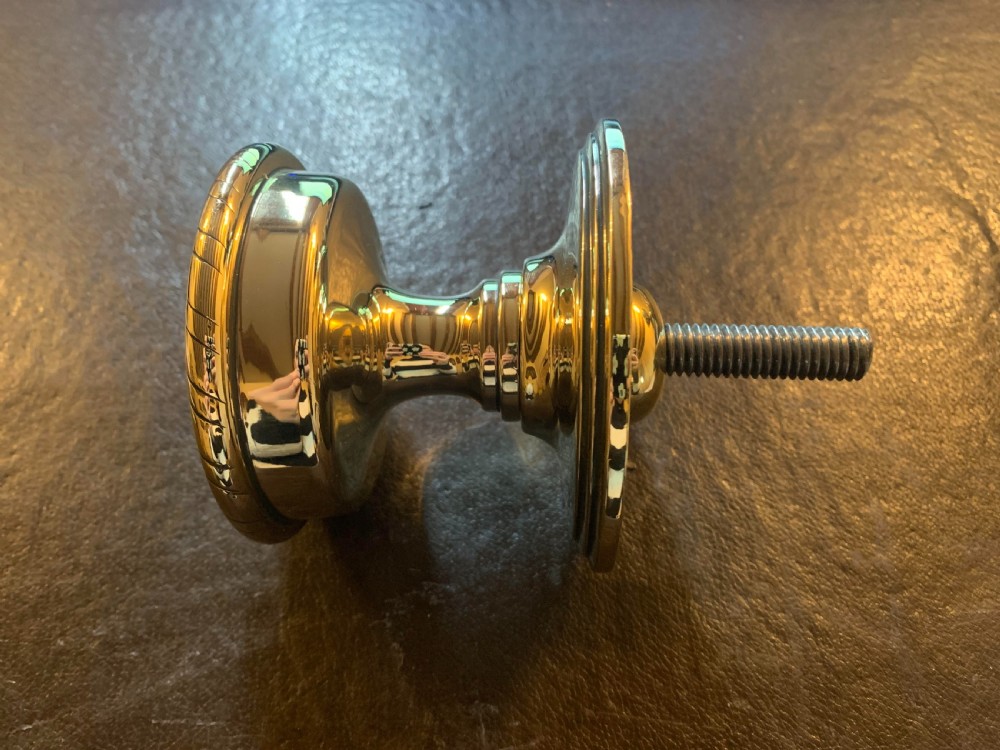 A polished brass centre door knob featuring a stepped circular backplate and a rope-twist detailed edge. View IV
