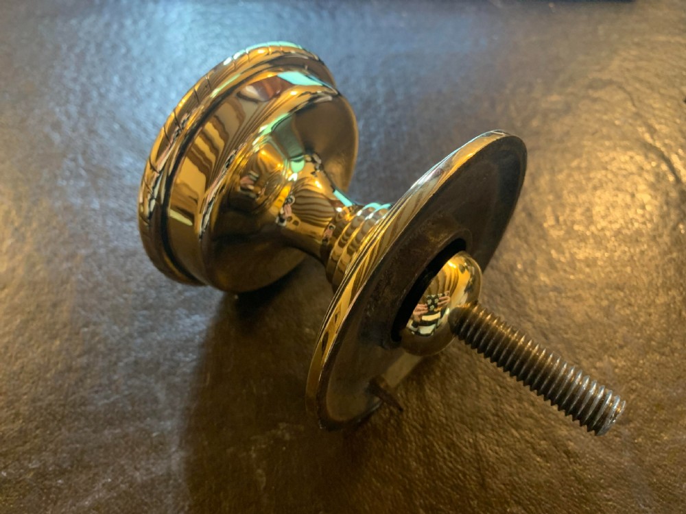 A polished brass centre door knob featuring a stepped circular backplate and a rope-twist detailed edge. View V