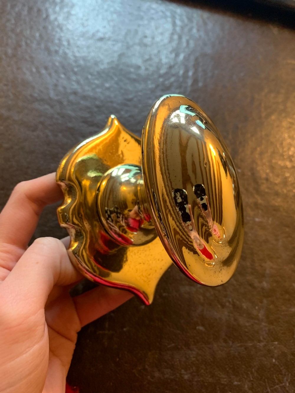 A polished brass Georgian centre door knob featuring an oval handle mounted to a shaped decorative backplate.