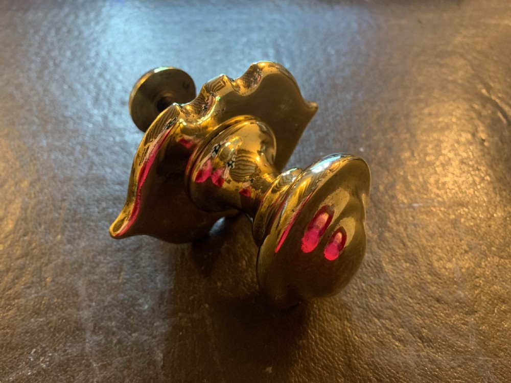 A polished brass Georgian centre door knob featuring an oval handle mounted to a shaped decorative backplate. View II