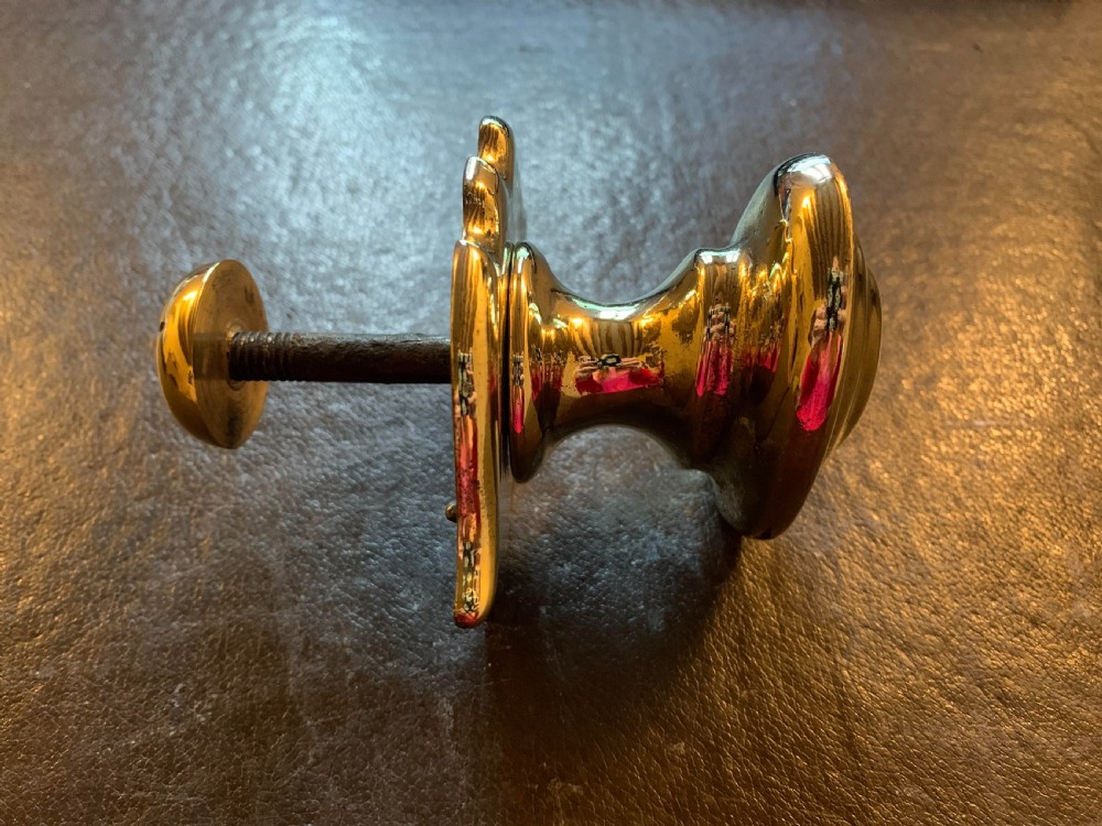 A polished brass Georgian centre door knob featuring an oval handle mounted to a shaped decorative backplate. View III